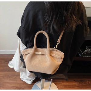 Detail of matte beige wing bag showing soft suede texture and gold metallic buckle