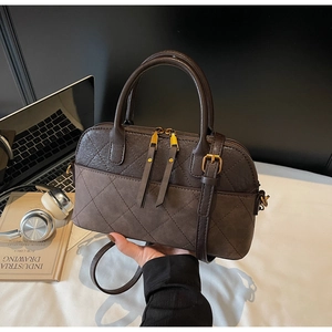 Detail of vintage quilted shell bag with brown suede patchwork and gold hardware