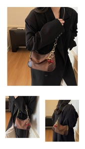 Detailed view of vintage brown leather crescent bag with chain strap and cherry charm