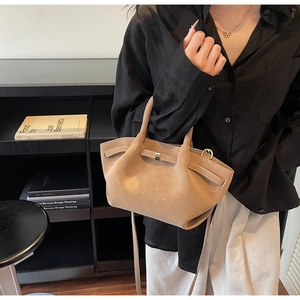 Detail of beige frosted leather handbag with dual handles and metal buckle