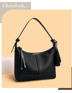 Detail of black textured faux leather baguette bag with diagonal embossed stripes and tassel