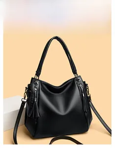 Close-up of black lychee grain leather tote bag with long tassel zippers and silver rings