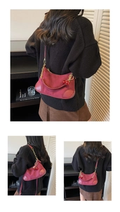 Detail of burgundy suede moon bag featuring gold chain and cherry charm accessory