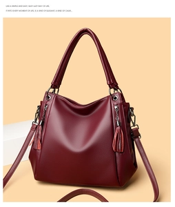 Detail of burgundy lychee-textured faux leather tote bag with tassels and shoulder strap