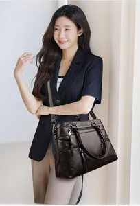 Detail of a dark brown leather tote bag showing multiple zipper pockets and smooth texture