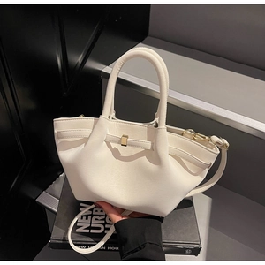 Close-up of cream pleated handbag featuring artistic folds and a gold rectangular buckle