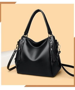 Detail of black pebbled leather tote bag with silver zippers and long tassel charms