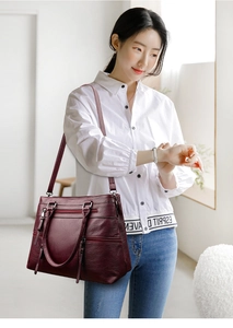 Detail of burgundy vintage tote bag showing multi-zipper pockets and leather texture