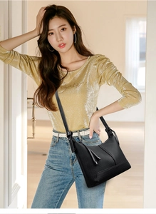 Detail of black woven baguette bag with metallic tassel charms and slim shoulder strap