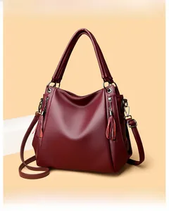 Detail of burgundy pebbled leather tote with side fringe and gold-tone strap clips