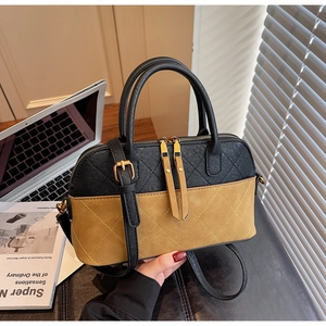 Detail of two-tone quilted bag with gold hardware and fine stitching on leather