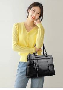Detail of black pebbled leather tote bag with three functional front zipper pockets