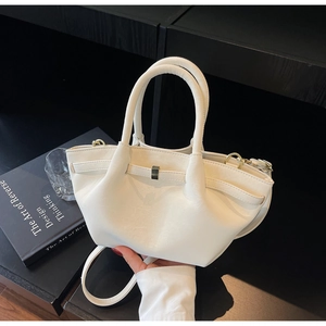 Detail of matte cream wing bag showing golden metal buckle and pleated wing design