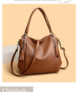 Close-up of brown lychee leather tote bag with stylish tassel zippers and shoulder strap