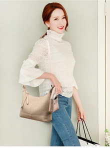 Detailed texture of beige woven shoulder bag with adjustable strap and coin purse charm