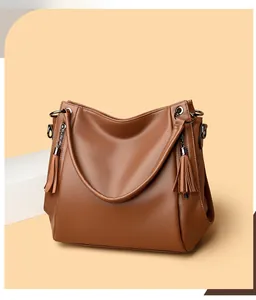 Detail of brown litchi pattern leather tote with long side tassels and matte hardware