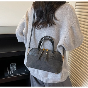 Quilted shell bag shown on model with shoulder strap in a stylish indoor setting