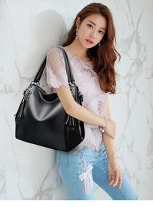 Detail of black pebbled leather tote bag with stylish side tassel and large capacity