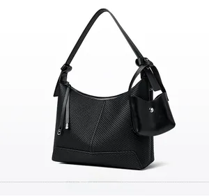 Close-up of black textured leather handbag with diagonal patterns and silver zipper detail
