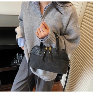 Détail du sac matelassé noir avec double fermeture éclair et finitions dorées élégantes