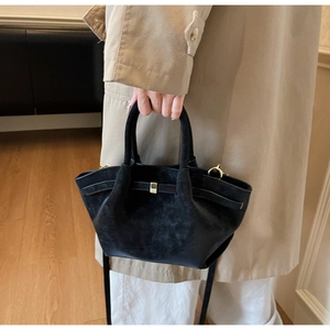 Detailed close-up of matte black wing bag with elegant gold buckle and folded textures