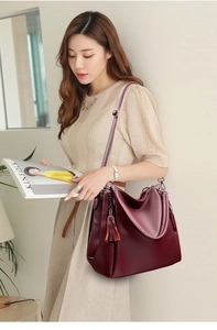 Detail of burgundy lychee leather tote with tassel charm and adjustable strap