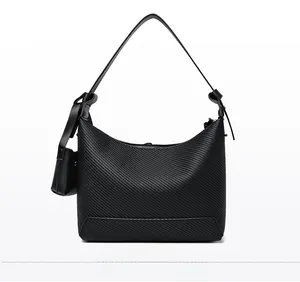 Detail of black textured baguette bag with diagonal embossing and small side pouch