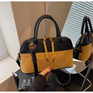 Détail du sac à main matelassé bicolore avec fermeture éclair et reflet élégant du miroir
