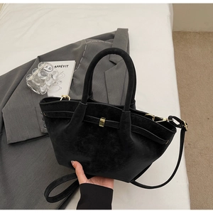 Close-up of matte black wing bag with pleated detail and golden metal hardware accent