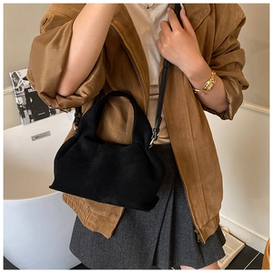 Detail of black suede cloud dumpling bag with gold hardware shown in lifestyle setting