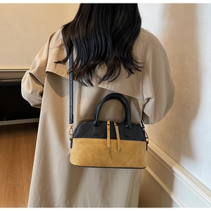 Détail du sac cabas bicolore avec matelassage en losanges et longs glands sur trench-coat