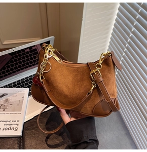 Detail of vintage brown suede shoulder bag with gold chain and red ball charm