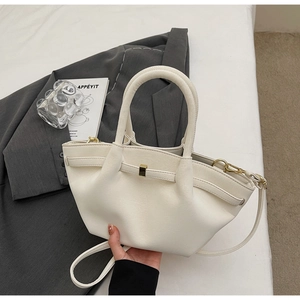 Detail of cream white pleated handbag with gold hardware and removable shoulder strap
