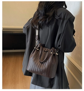 Detailed view of dark brown woven bucket bag with patterned textile shoulder strap on model