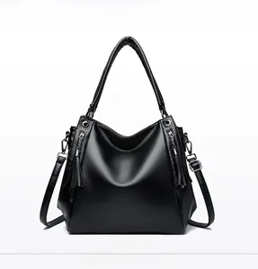 Detailed front view of black hobo bag with pebble leather texture and tassel zippers