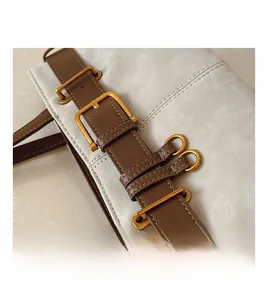 Détail macro du sac en daim et cuir avec une boucle de ceinture dorée au style vintage