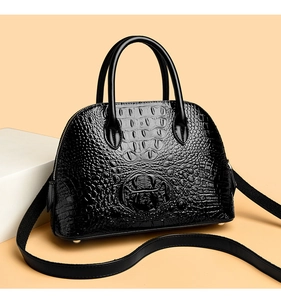 Close-up of black crocodile pattern leather handbag with metallic studs on base