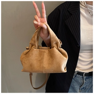Detail of camel suede bucket bag featuring elegant cloud-shaped pleats and top handle