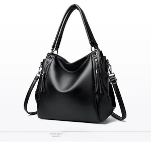 Detail of black pebbled leather tote bag with silver hardware and decorative tassel zipper