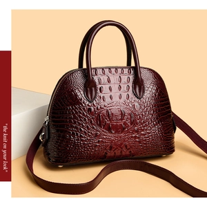 Detail view of wine red shell bag with crocodile texture and gold metal hardware hooks