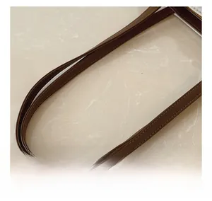 Détail de la bandoulière en cuir marron avec double surpiqûre sur un sac sous le bras