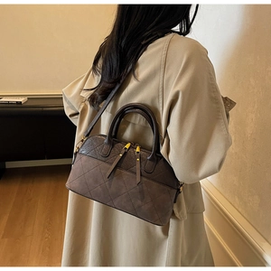 Détail d'un sac porté épaule matelassé marron foncé avec double zip et trench beige
