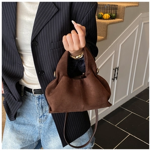 Detail of dark brown matte suede cloud bag with soft pleats and gold metal hardware