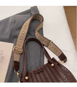 Detail of brown woven bucket bag featuring vintage patterned wide strap and gold hardware