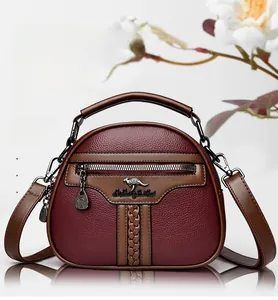 Macro shot of litchi-grain PU leather handbag with metal kangaroo logo and woven trim