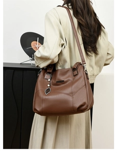 Sac cabas marron foncé avec pendentif feuille porté à l'épaule par un mannequin