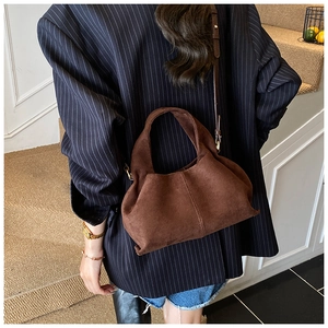 Close-up of deep brown suede bucket bag showing soft pleats and fine texture detail