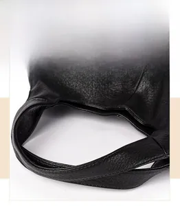 Detail of reinforced handles and litchi grain texture on this black leather tote bag