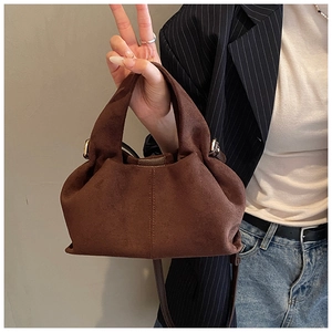 Detail view of the soft dark brown suede texture and pleated folds on the cloud dumpling bag