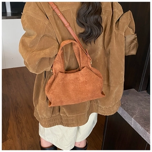 Detail of caramel suede cloud bag showing pleats and adjustable shoulder strap on model